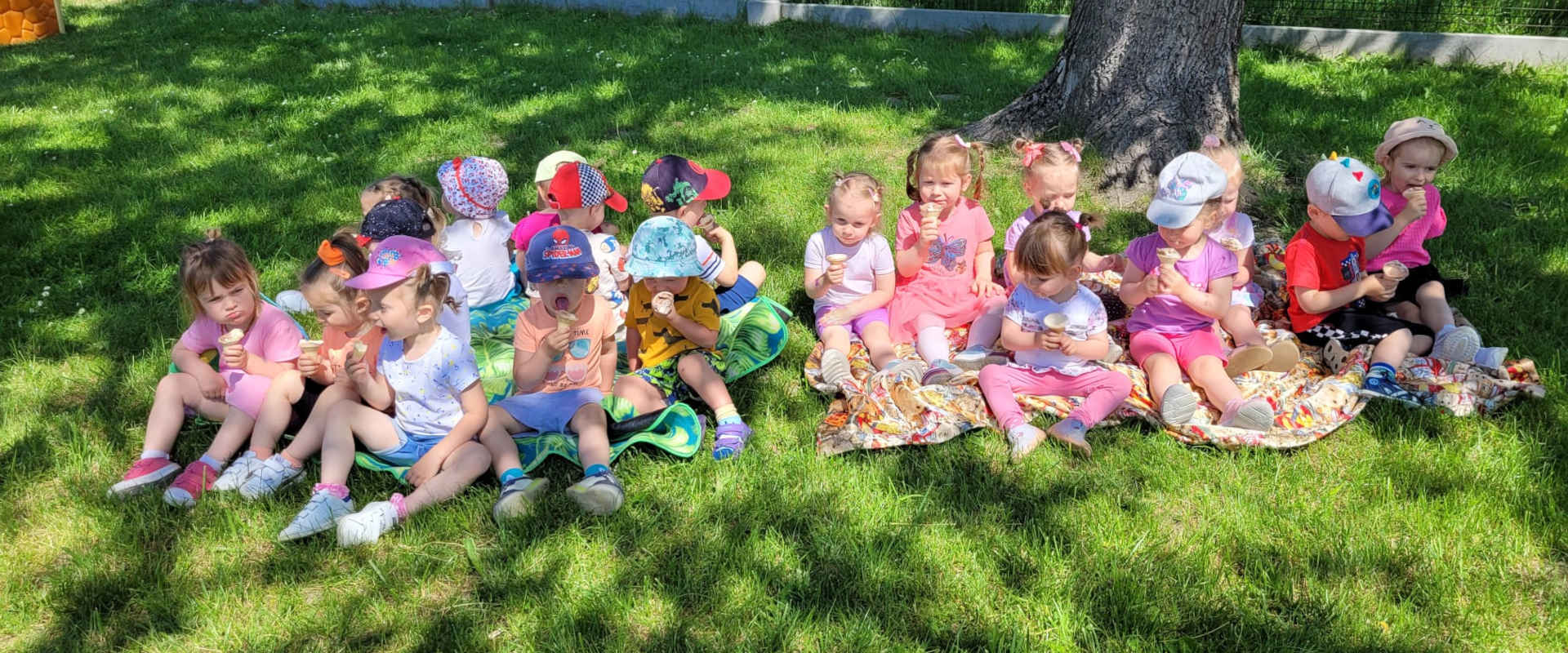 Dzieci pod drzewem jedzą słodycze